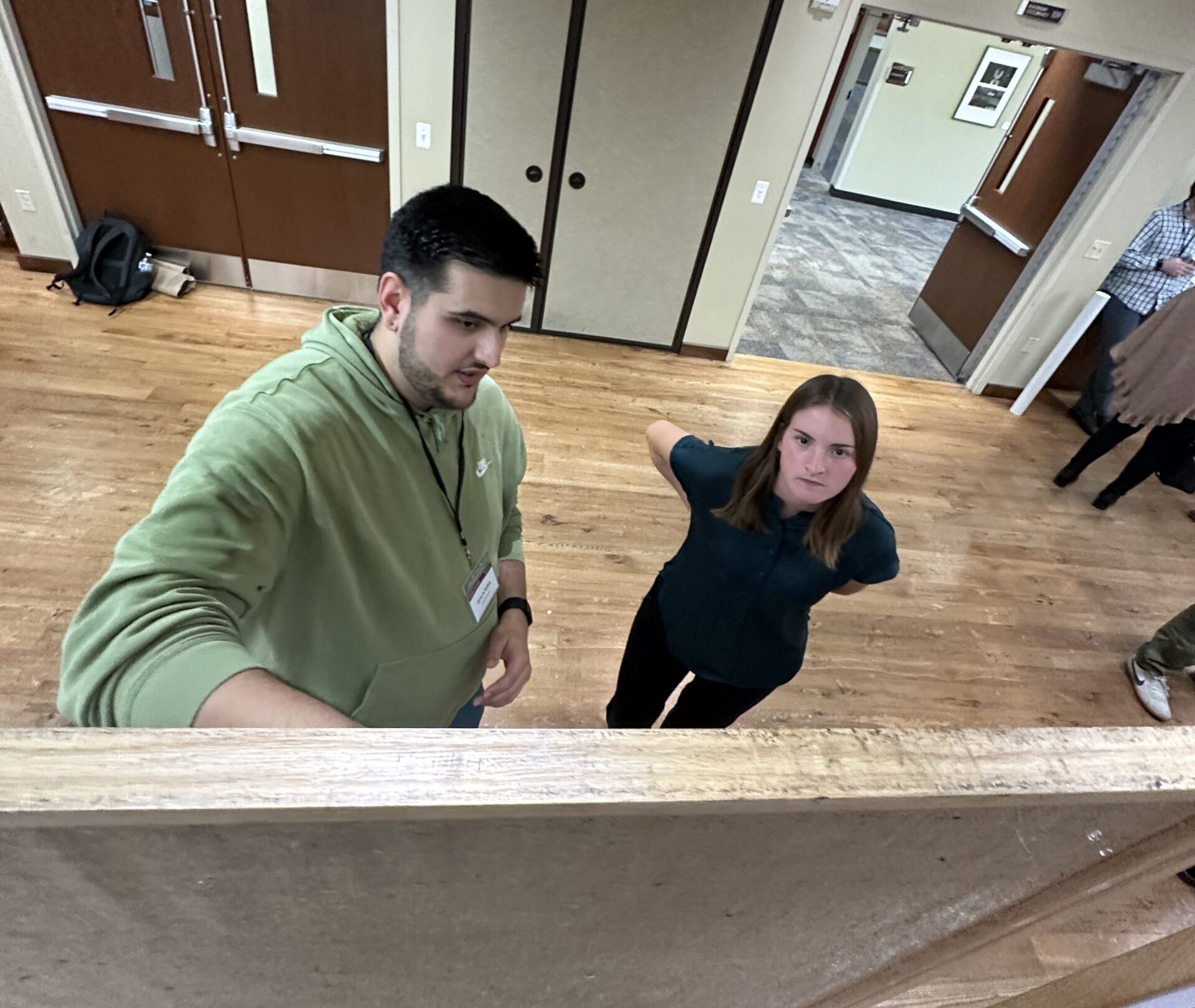 An image taken over the top of poster board of Cyrus explaining his poster to Katelyn, Rachel's sophomore undergrad assistant at Diabetes Day on September 11th, 2025