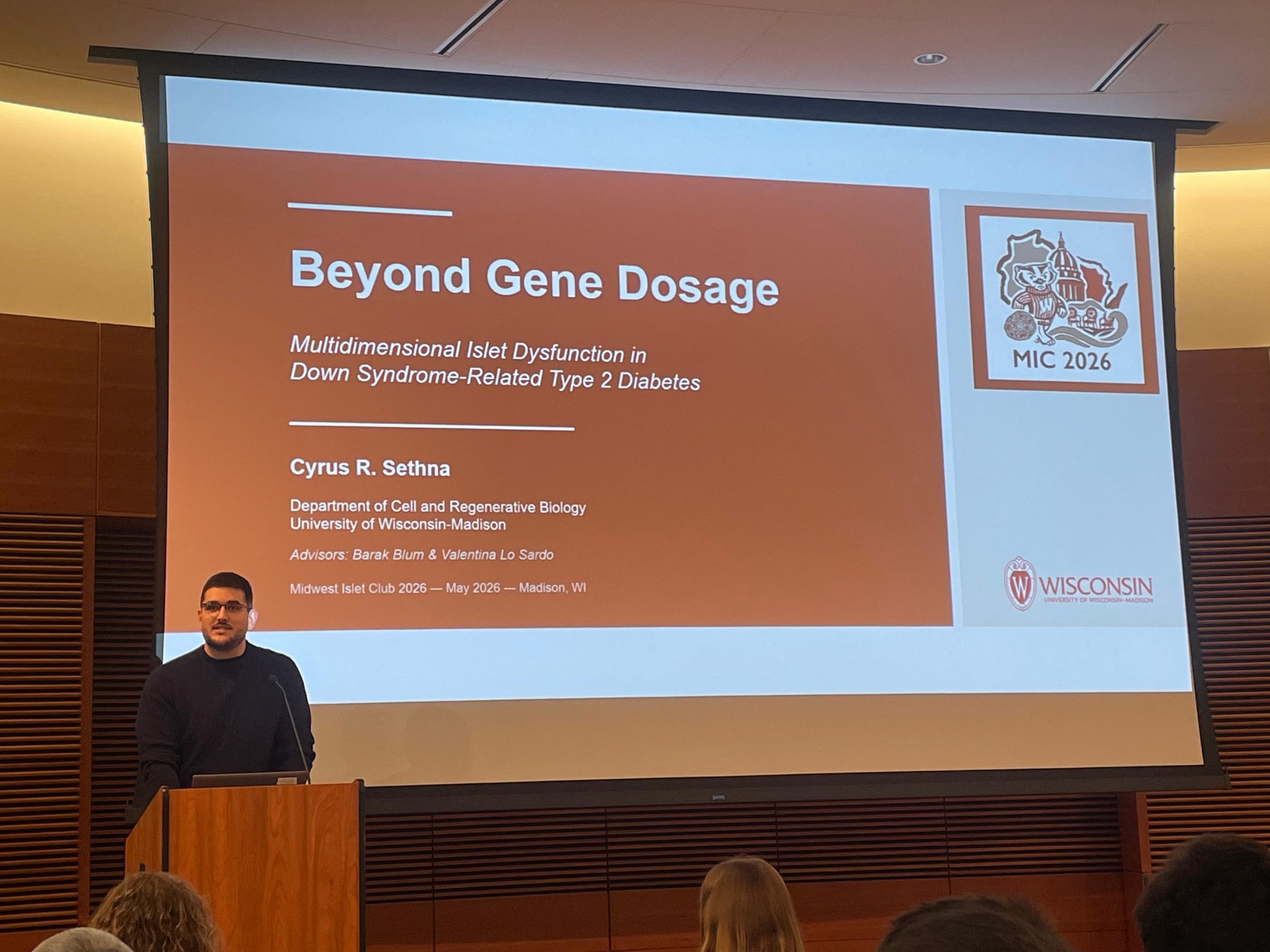 Cyrus at a podium about to begin his short talk titled Beyond Gene Dosage at the Midwest Islet Club, May 2026